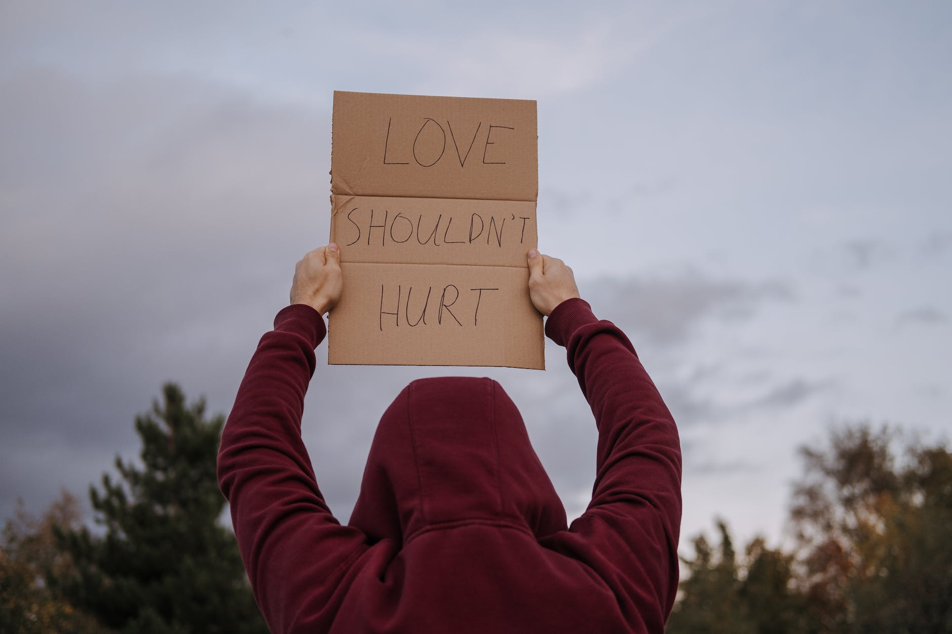Love Shouldn't Hurt - man holding up a sign saying this